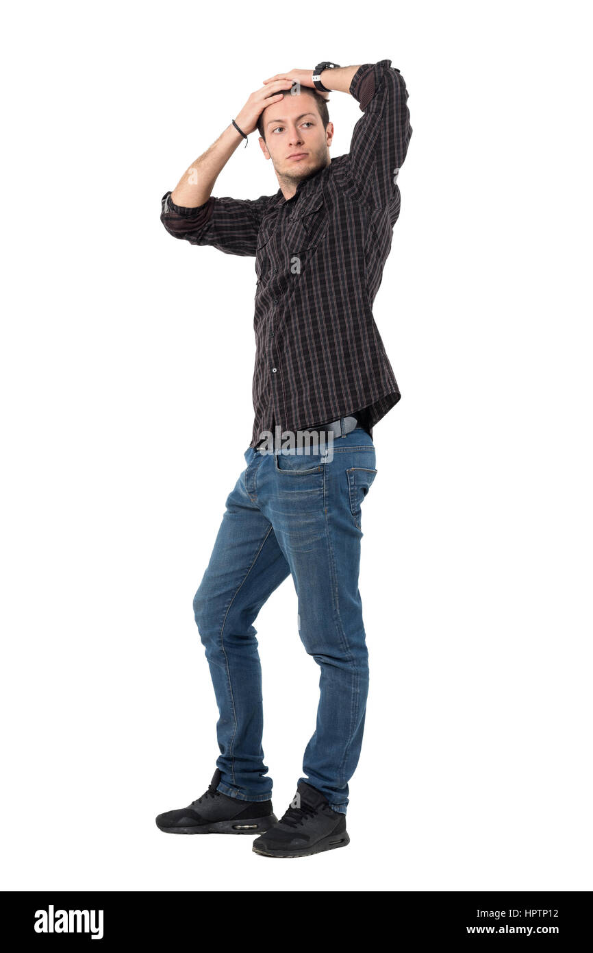 Jeune homme séduisant en jeans et chemise à carreaux avec les mains de la posture de la tête. La longueur du corps complet isolé portrait sur fond blanc. Banque D'Images