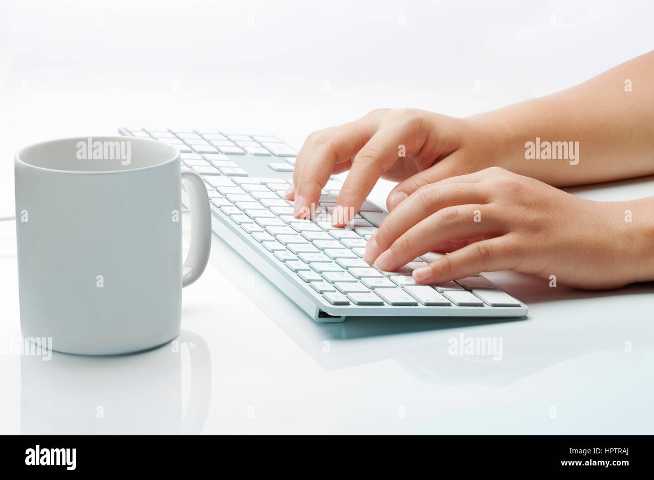 Mains tapant à un clavier et une tasse de café à l'arrière-plan blanc. Ambiance lumineuse de travail. Banque D'Images