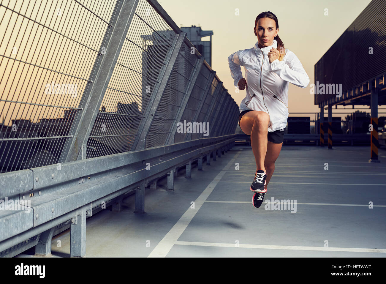 Photo de jeune femme sprint sur le parking sur le toit Banque D'Images