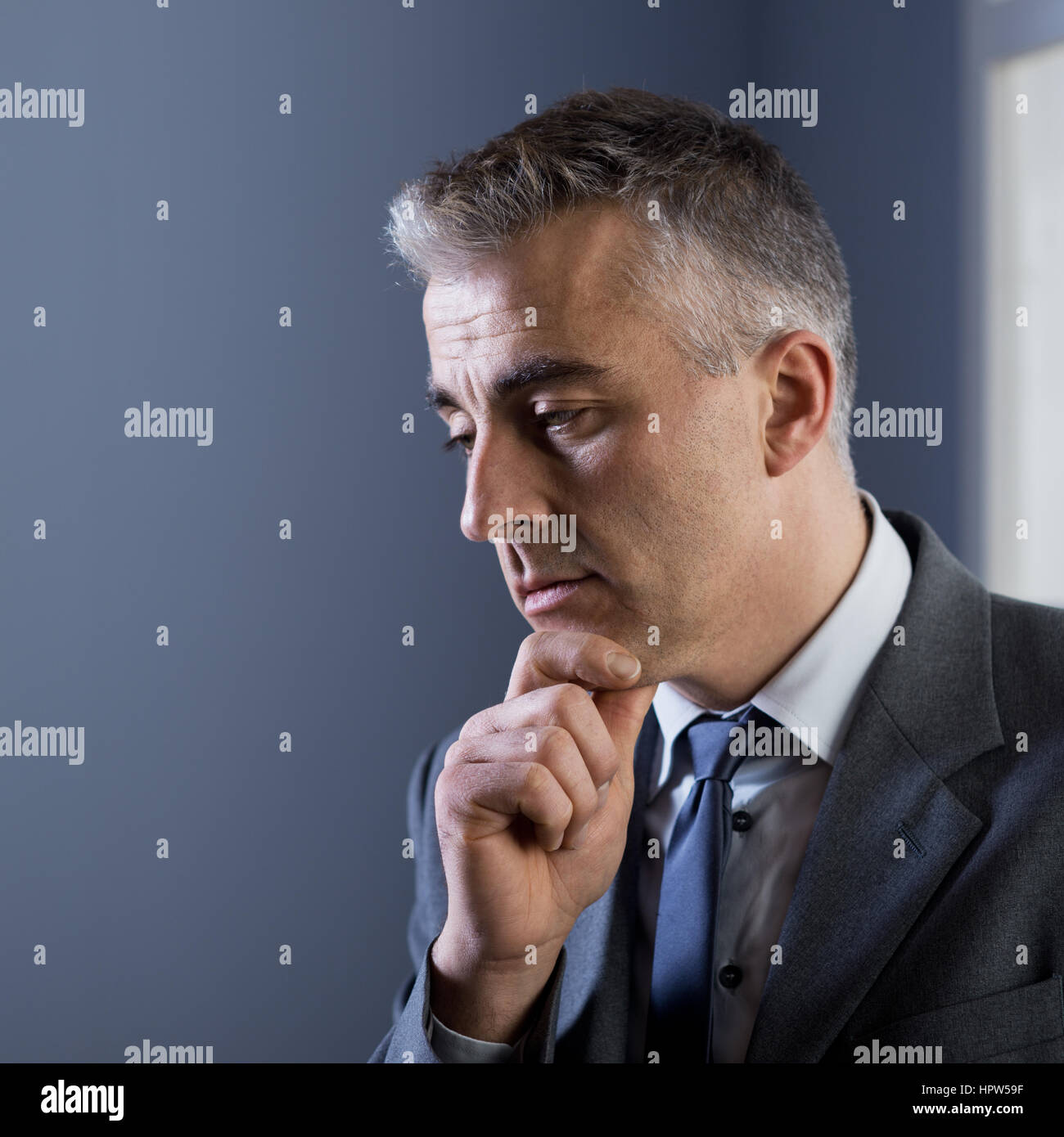 Pensive businessman with hand on chin à l'office. Banque D'Images Pensive businessman with hand on chin à l'office. Banque D'Images