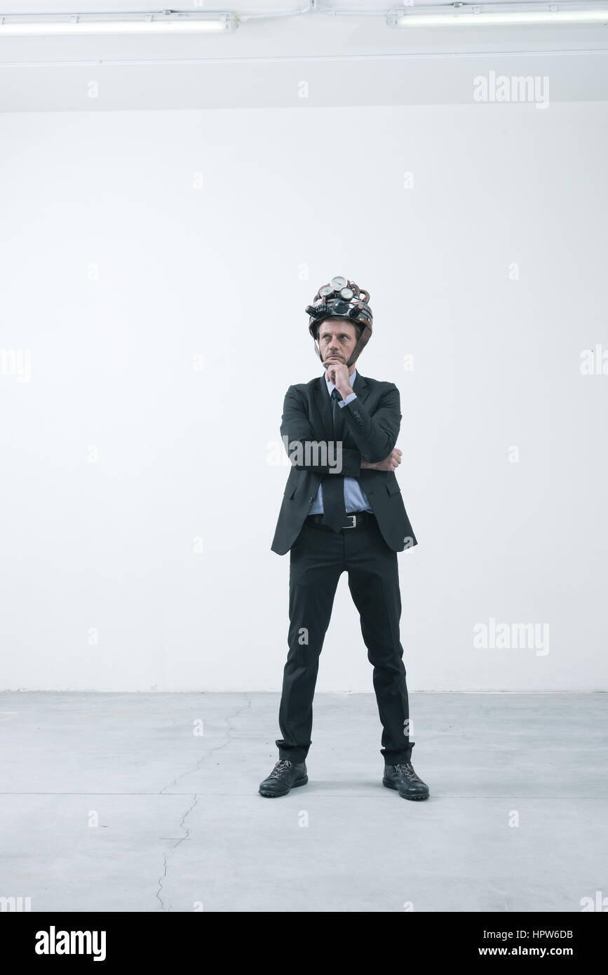 Confident businessman thinking with hand on chin portant casque steampunk Banque D'Images Confident businessman thinking with hand on chin portant casque steampunk Banque D'Images