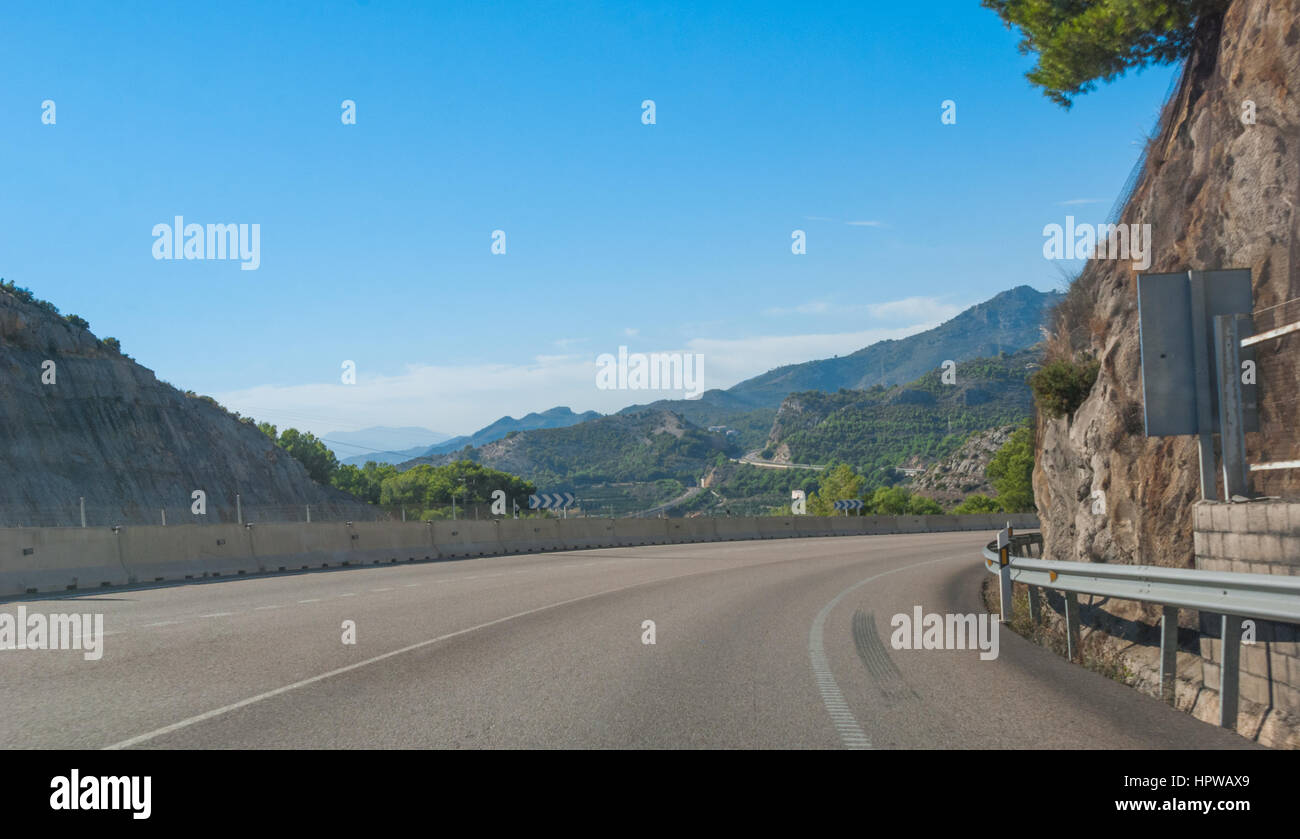 Dans le virage - Soleil sur l'autoroute côtière espagnole. Vue de conduite de Foothills et les chaînes de montagnes, sur les bords de l'Europe continentale dans les régions rurales de l'Espagne. Banque D'Images