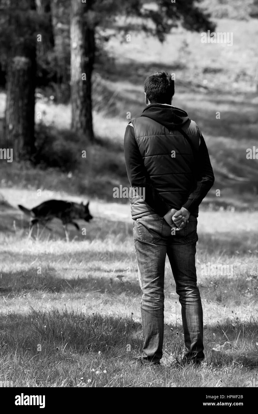 L'homme à pied avec son chien dans la forêt ensoleillée, image en noir et blanc Banque D'Images