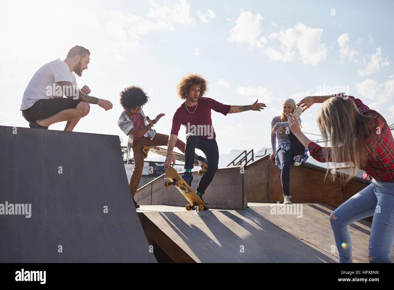 Femme amis masculins photographiant le skate sur la rampe de skate park Banque D'Images
