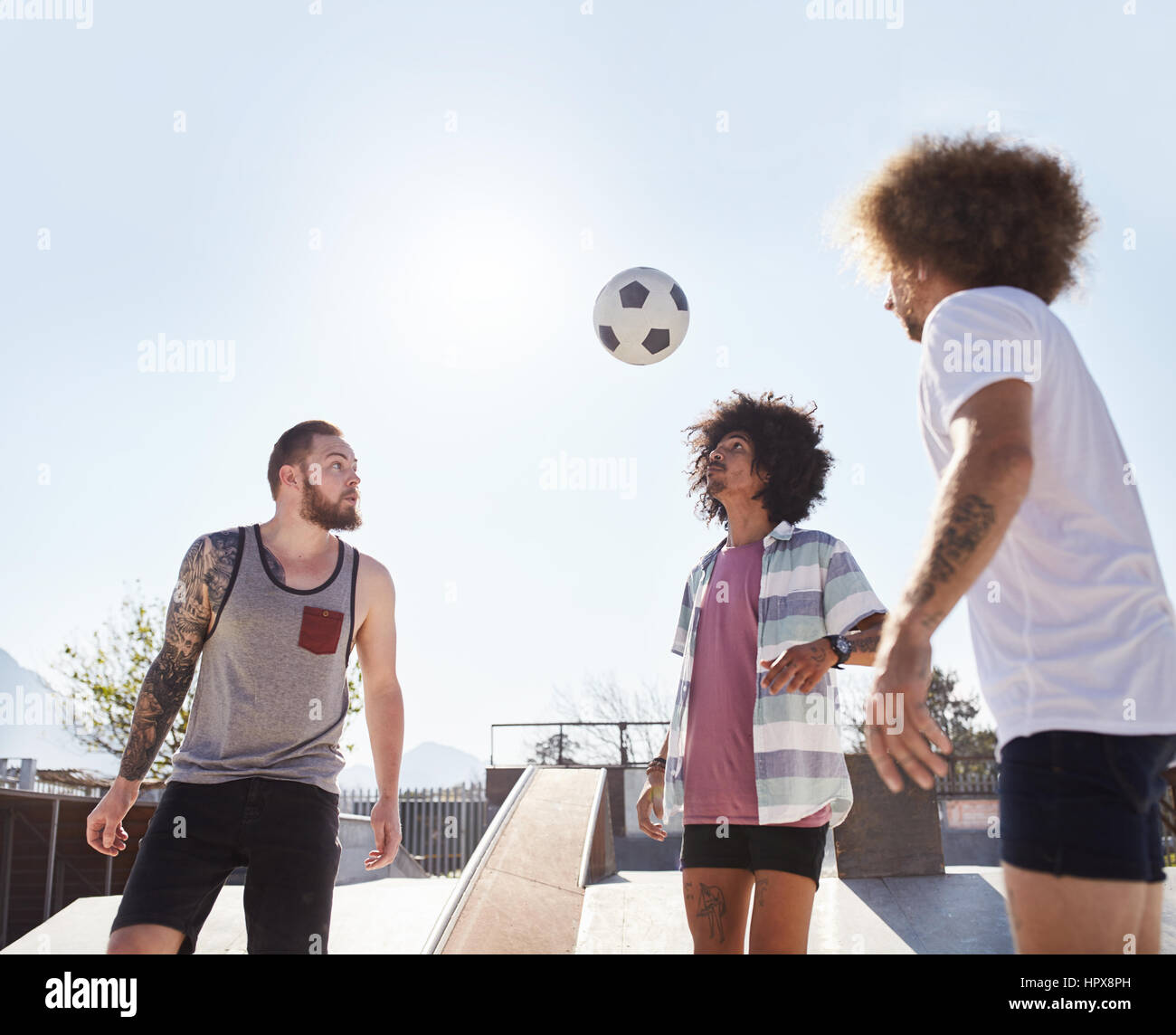 Amis à jouer au soccer à sunny skate park Banque D'Images