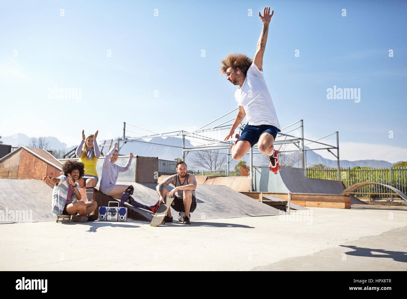 L'observation d'amis et acclamer man en patins à roulettes de skate park Banque D'Images