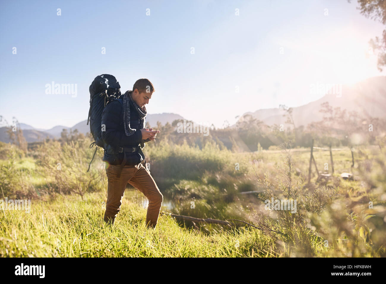 Jeune homme avec sac à dos randonnée, boussole contrôle à distance sur le terrain, sous le soleil Banque D'Images