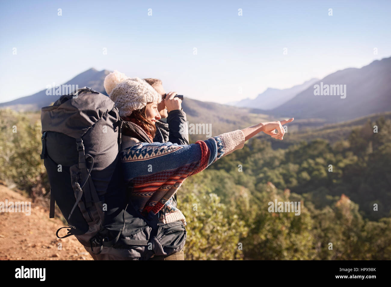 Jeune couple hiking, regardant le sunny view with binoculars Banque D'Images