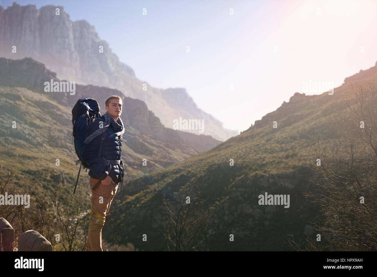 Jeune homme avec sac à dos randonnée, regardant sur la montagne ensoleillée Banque D'Images