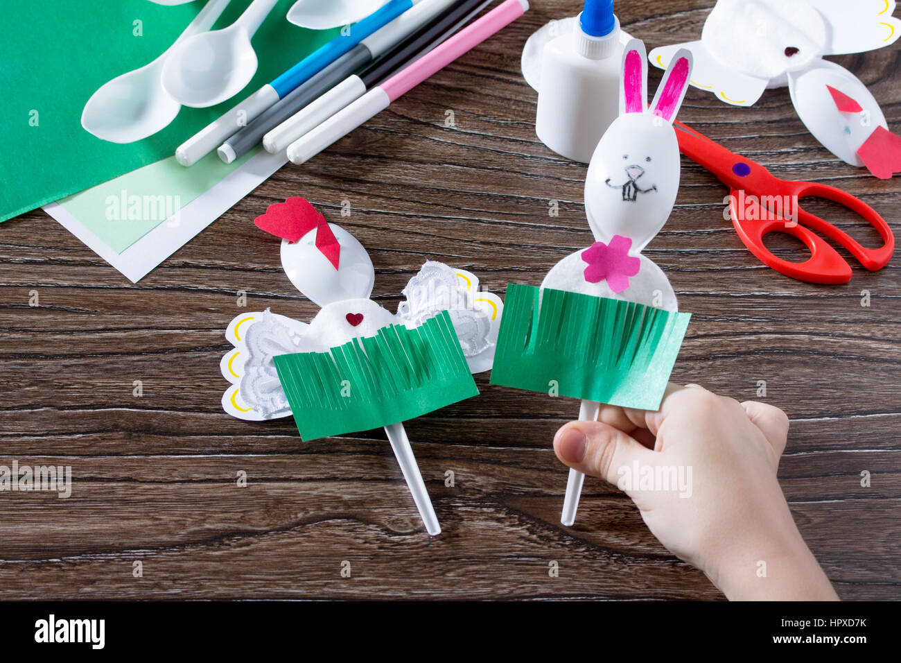 L'enfant crée un jouet cadeau de Pâques lapin de Pâques. Papier, de la  colle et des cuillères en plastique sur une table en bois. Fait à la main.  Projet d'art pour enfants,