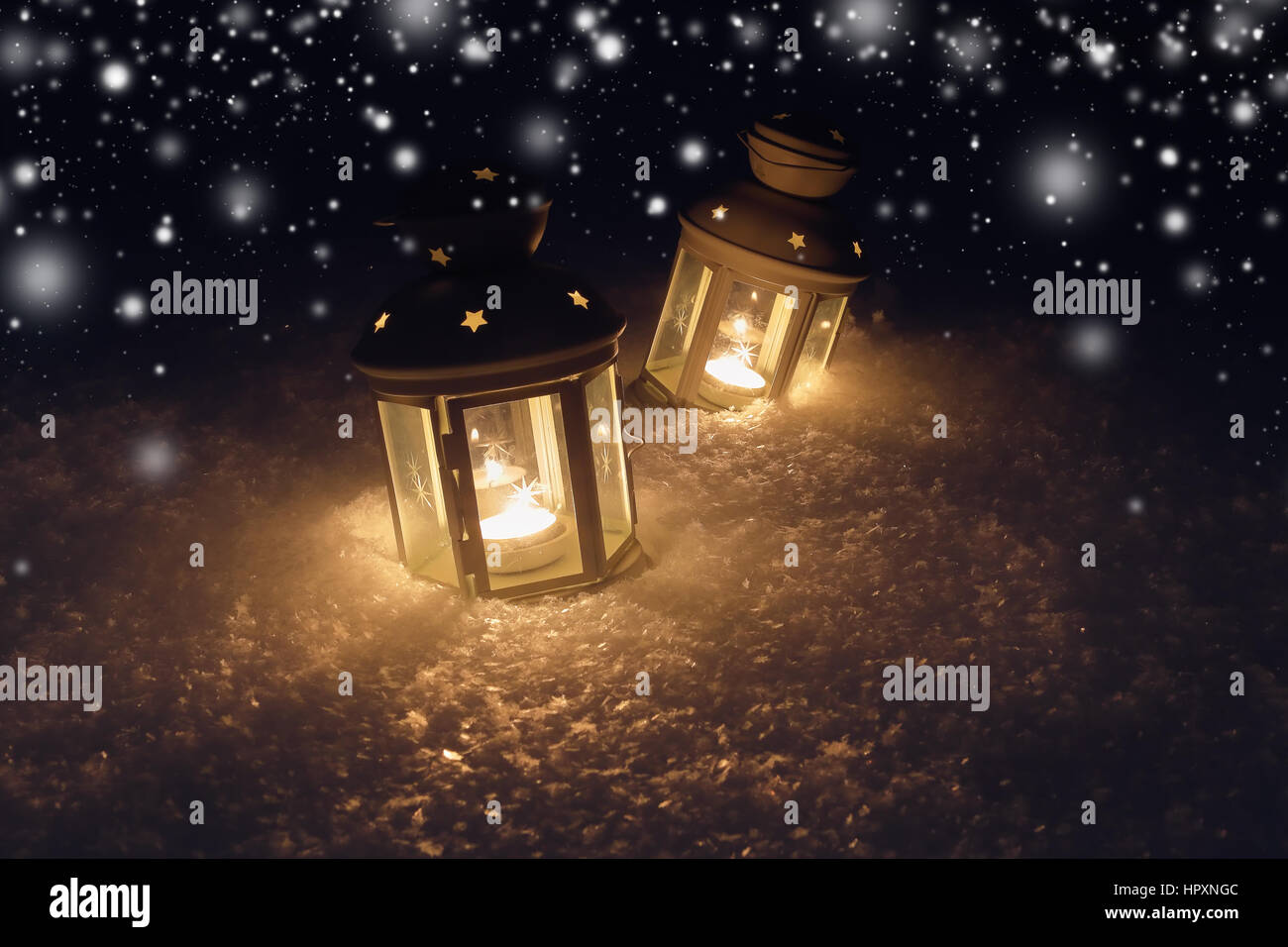 Des lumières décoratives de Noël avec des bougies sur la neige. Flocons blancs à Noël la nuit. Arrière-plan de nuit avec les lumières. Banque D'Images