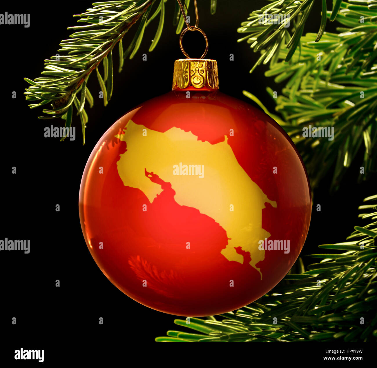 Une babiole rouge avec la forme d'or du Costa Rica accroché sur un arbre de Noël isolé sur noir.(série) Banque D'Images