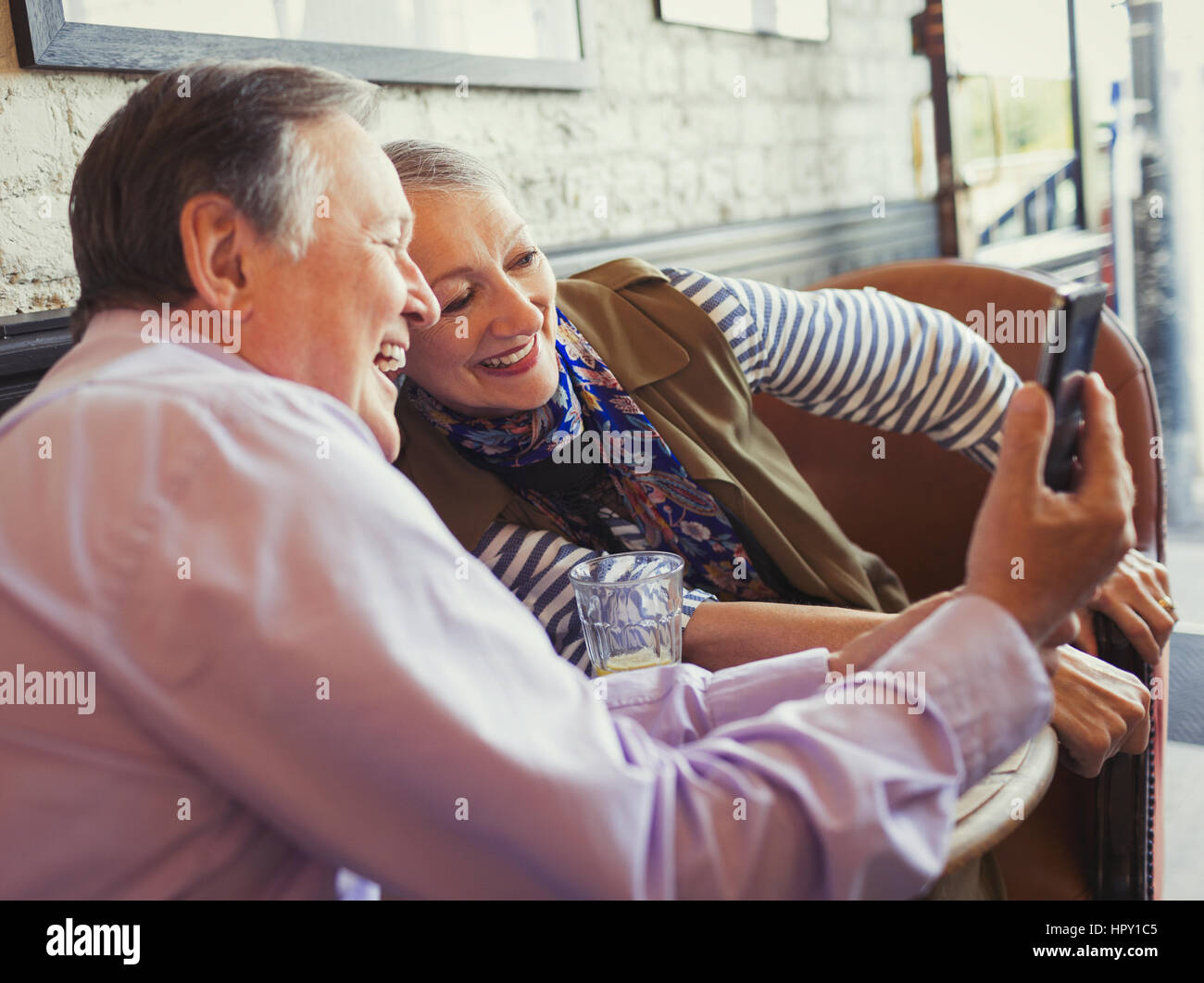 Smiling woman with camera phone selfies at cafe table Banque D'Images