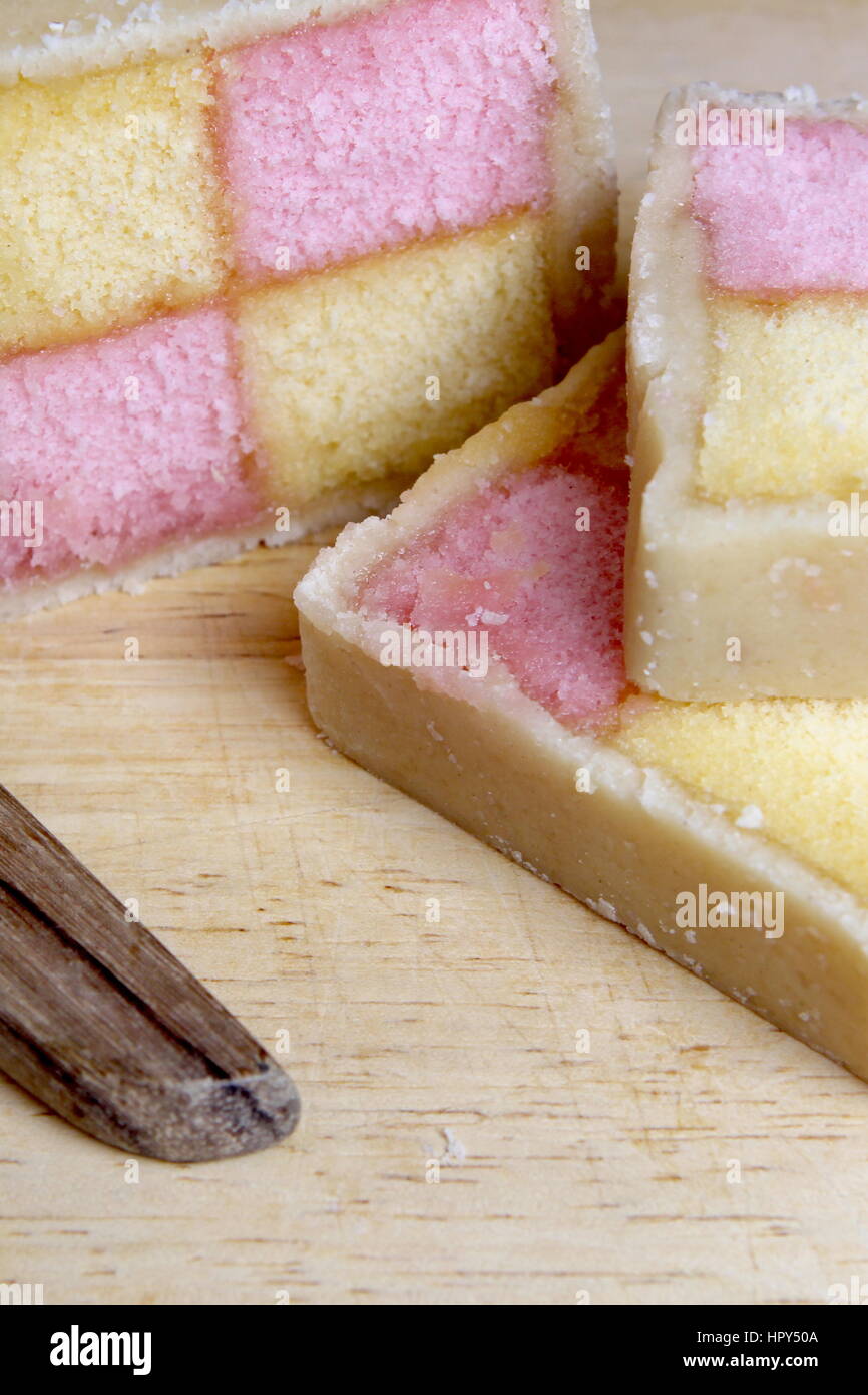 Battenberg fraîchement coupé au couteau à gâteau. Recouvert d'éponge rose et jaune en massepain Banque D'Images