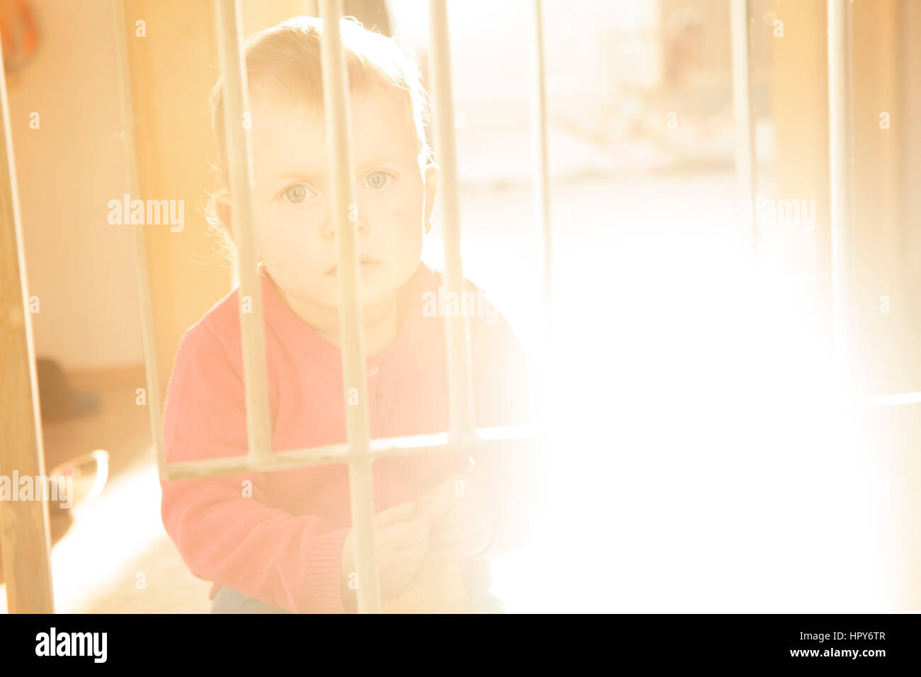 Little baby girl fermé derrière les barreaux Banque D'Images