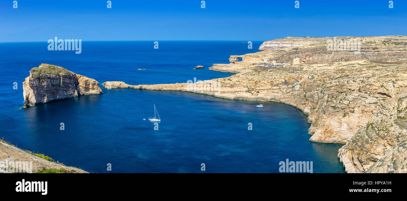 Gozo, Malte - Vue Panoramique vue sur l'horizon de Dwejra bay avec des champignons Rock, Fenêtre d'Azur et voilier sur une chaude journée d'été de nice Banque D'Images