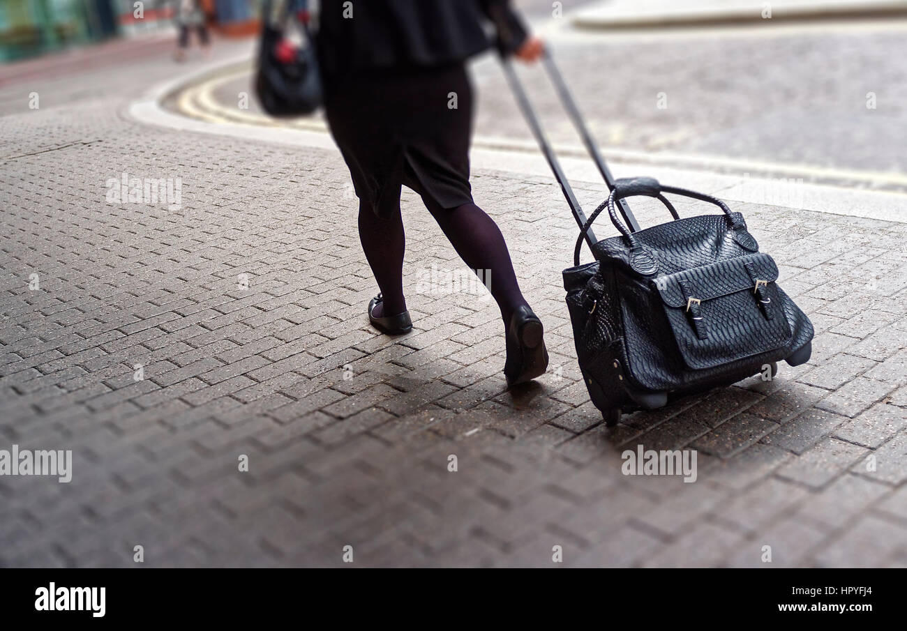 Woman Pulling Rolling Bag le long trottoir Banque D'Images