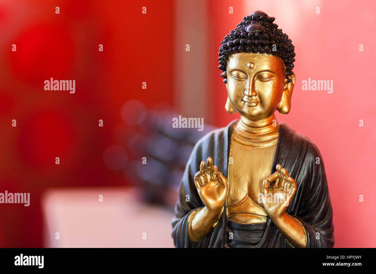 Sculpture bouddha devant un fond rouge Banque D'Images