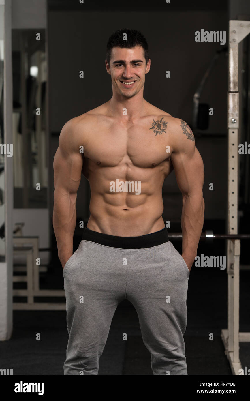 Bel homme Soyons forts dans la salle de sport et Flexing Muscles musculaire - Fitness Model Posing Bodybuilder athlétiques exercices après Banque D'Images