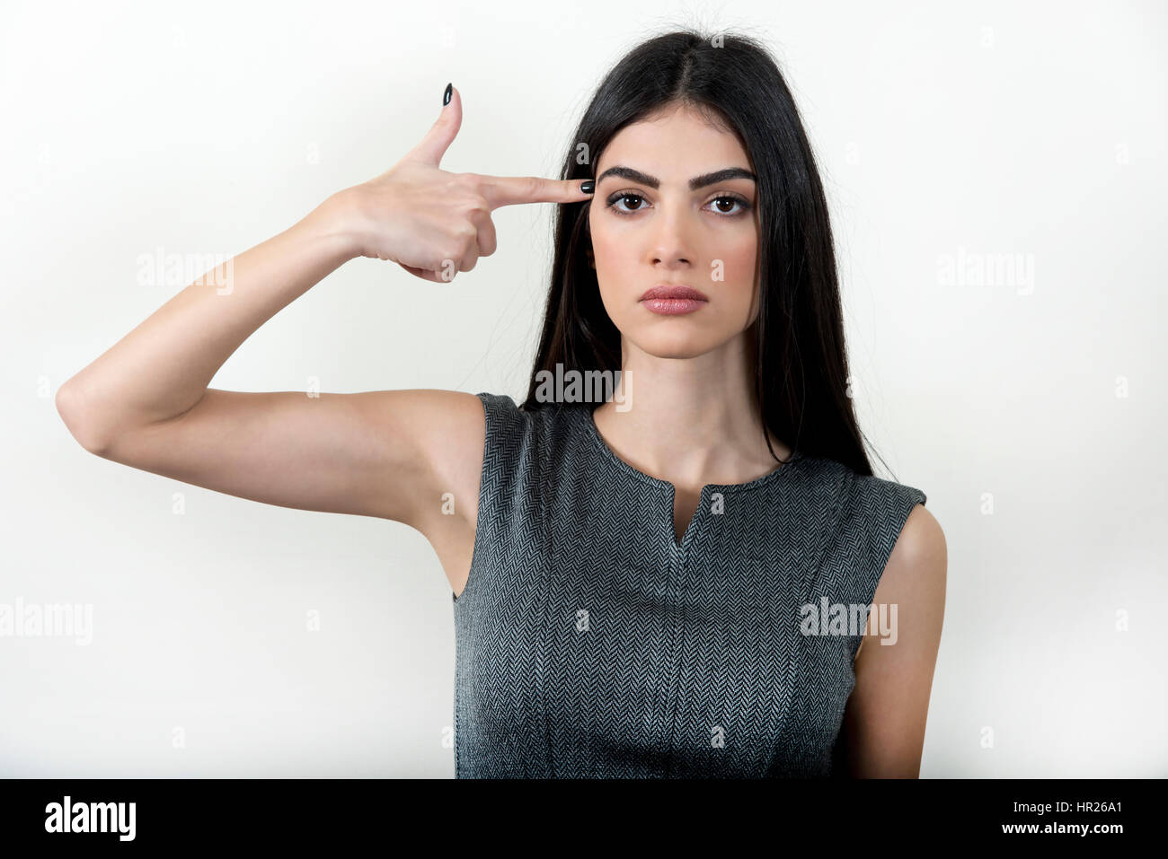 Jeune femme d'affaires pointant son doigt sur sa tête comme une arme, en faisant semblant de faire exploser la tête. Banque D'Images