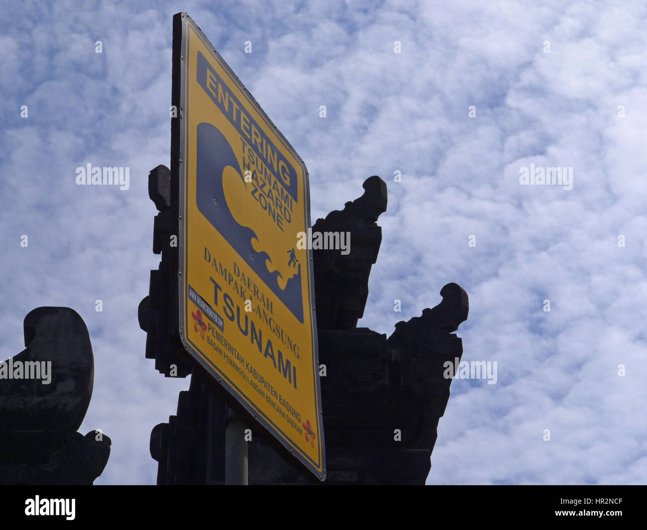 Zone de danger Tsunami signer avec les détails de l'architecture de temple de la mer à l'arrière. Bali, Indonésie Banque D'Images