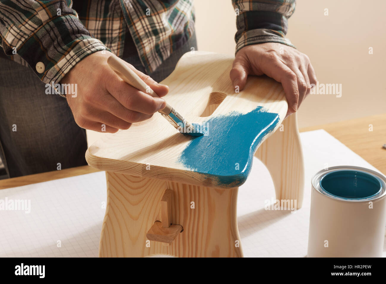 Vernissage à la main en bois Artisan un tabouret à la maison avec un revêtement bleu sur une table de travail, les mains close up Banque D'Images