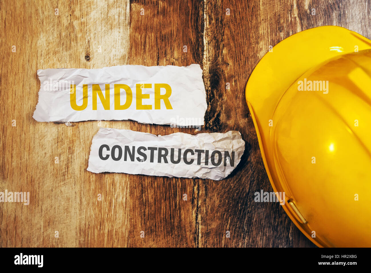 En construction concept avec casque de protection casque jaune sur le bureau en bois Banque D'Images