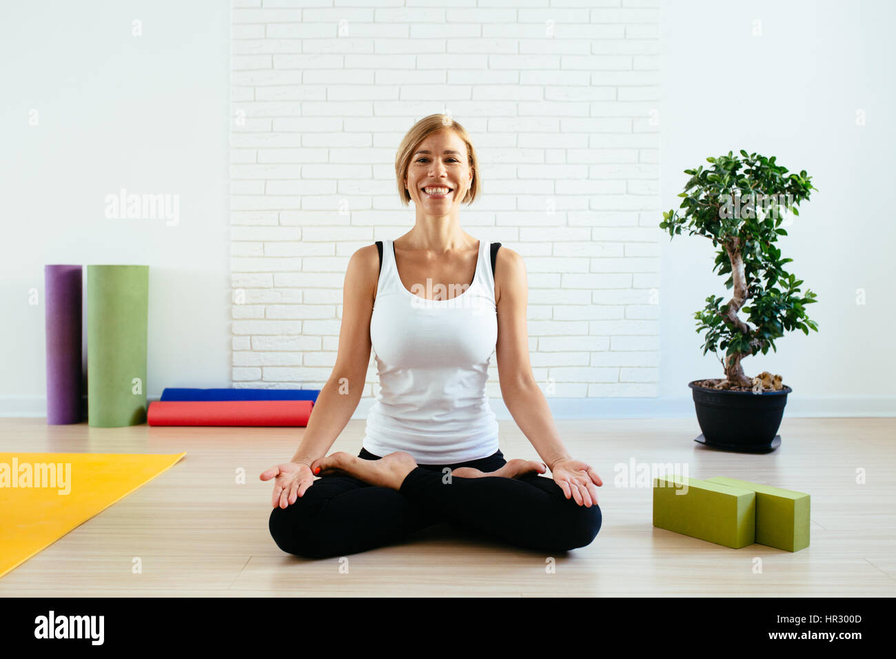 Woman doing yoga studio en position du lotus avec un sourire charmeur. Banque D'Images