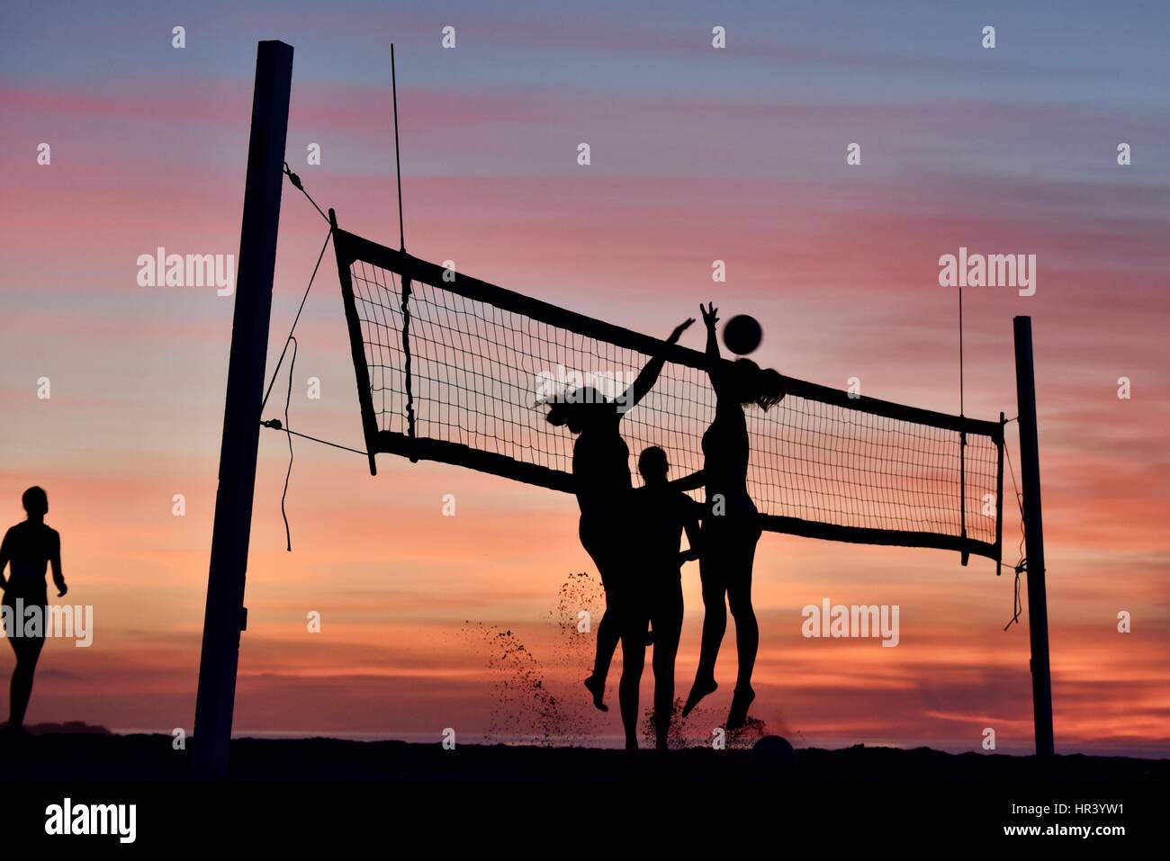 Silhouettes de joueurs de volley-ball féminin volley-ball pratique sur une plage au coucher du soleil à Mission Beach, San Diego, Californie. Banque D'Images