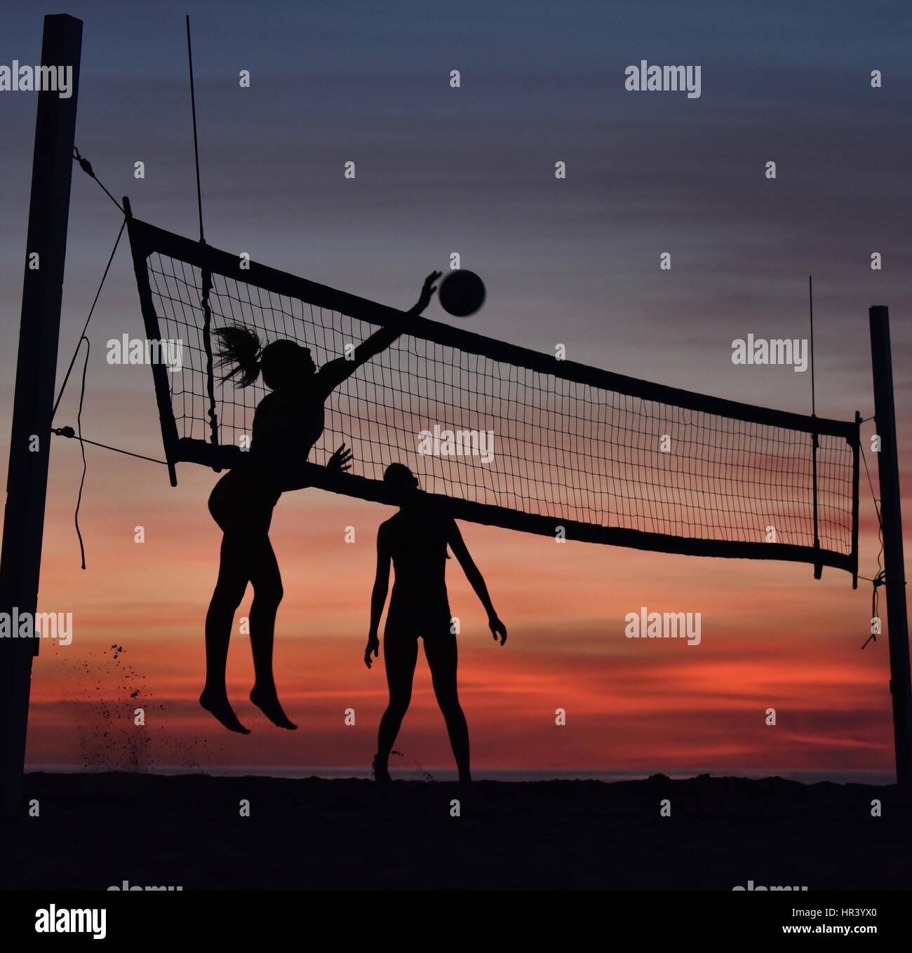 Silhouettes de joueurs de volley-ball féminin volley-ball pratique sur une plage au coucher du soleil à Mission Beach, San Diego, Californie. Banque D'Images