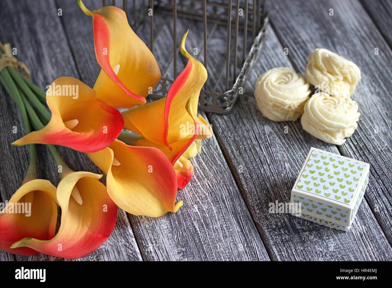 Bouquet de lis calla jaune orange avec de la guimauve et les petites boîte en carton gris sur un fond de bois. Banque D'Images