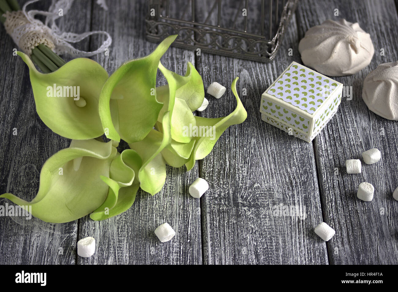 Bouquet de lis calla jaune vert avec des guimauves et boîte en carton gris sur un fond de bois Banque D'Images