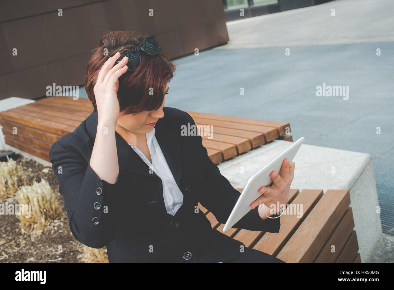 Jeune femme d'affaires authentique utiliser la tablette comme un miroir dans le quartier financier, à l'occasion d'un voyage Banque D'Images