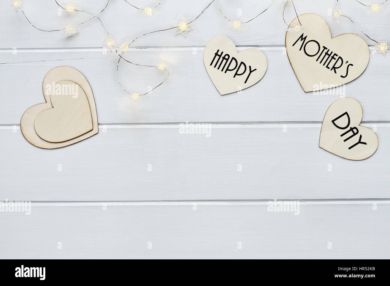 Vue aérienne de coeurs en bois et fairy lights avec message Happy Mother's Day sur une table en bois page contexte avec copie espace disponible. Banque D'Images