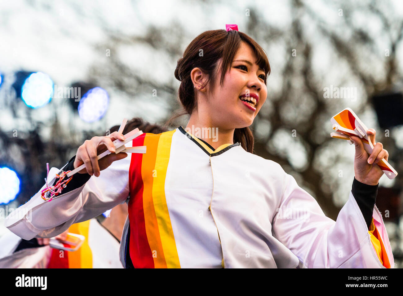 Danse Yosakoi Festival, au Japon. Close up, femme japonaise, danse, naruko holding bird battants, dans chaque main. Vue de la tête et des épaules. En soirée. Banque D'Images