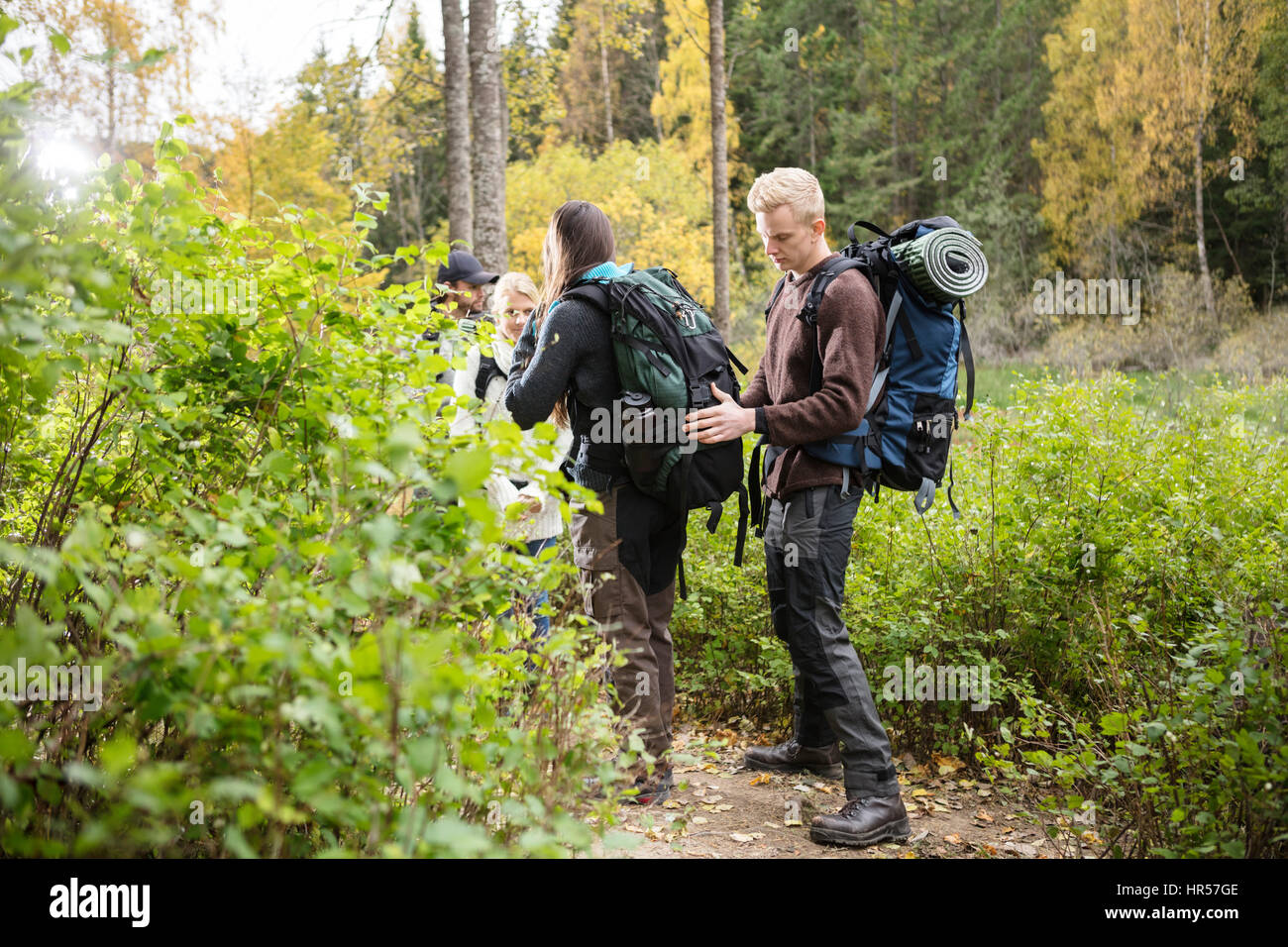 Jeune homme sac à dos d'amie de réglage au cours de la randonnée en forêt Banque D'Images