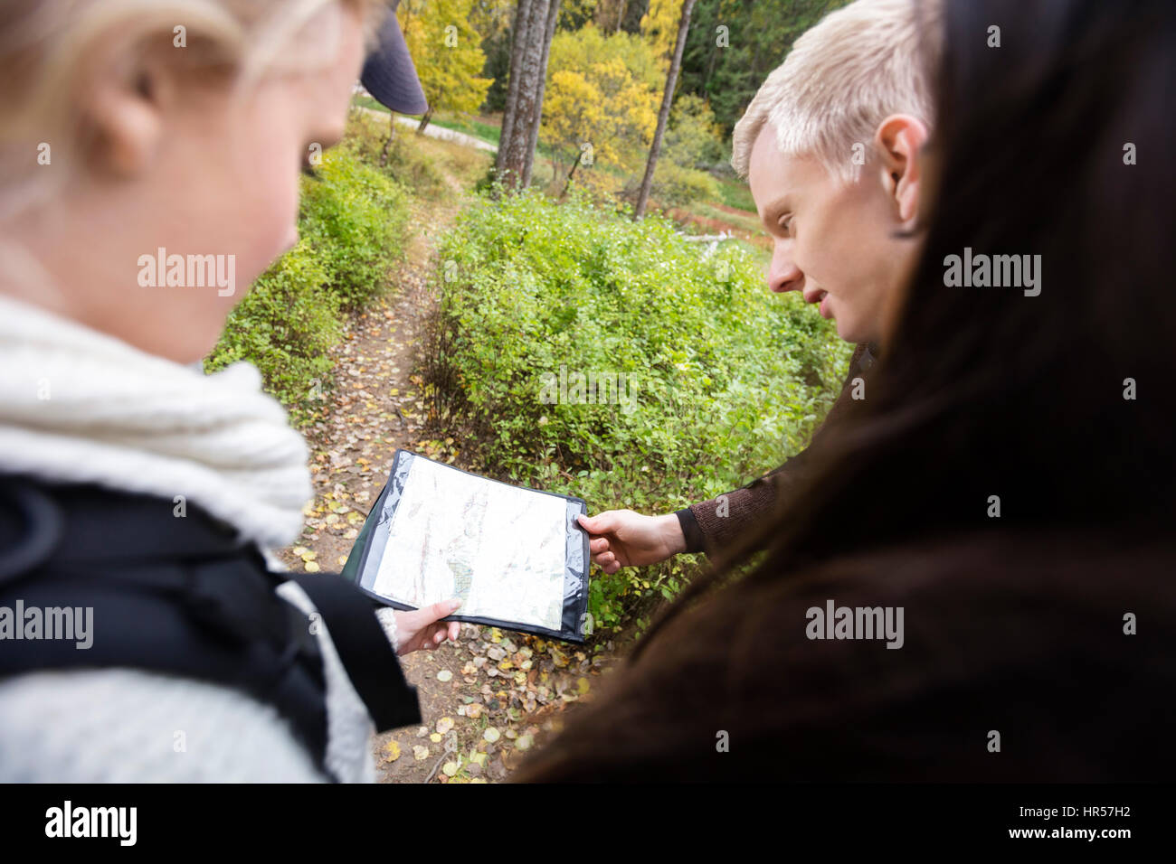 Amis multiethnique holding map lors d'une randonnée en forêt en automne Banque D'Images