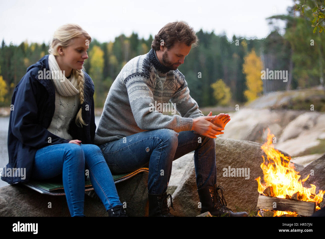 Jeune couple eux-mêmes par le réchauffement au cours d'un feu de camping Banque D'Images