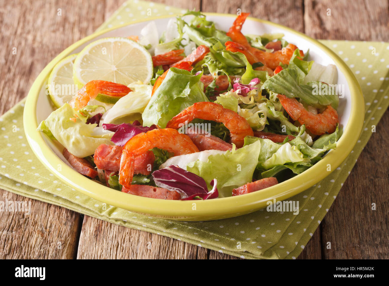 Salade de crevettes maison, chorizo, chaux, et mesclun close-up sur une plaque sur la table horizontale. Banque D'Images