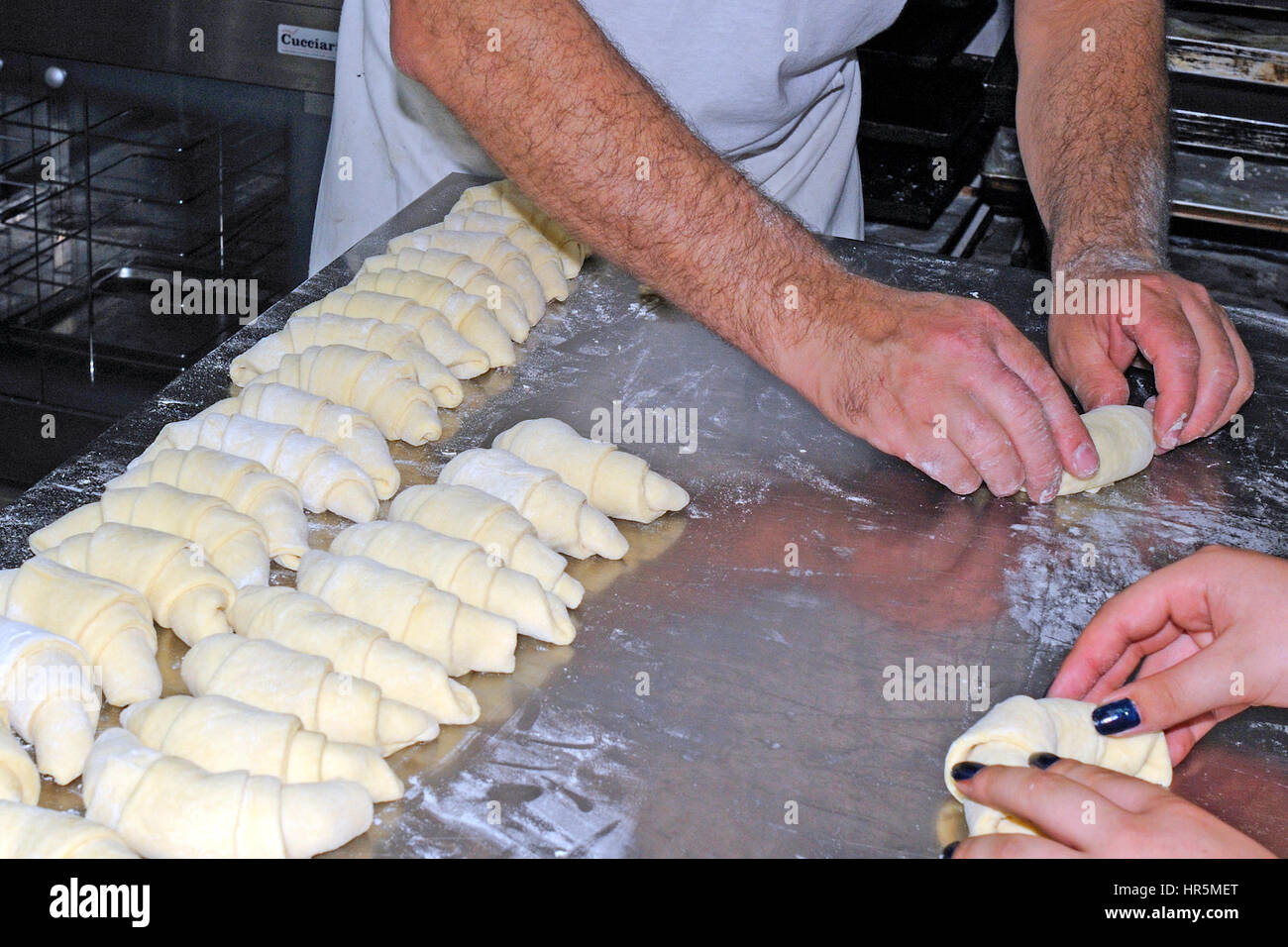 Un boulanger de travailler sur une surface farinée, rouler la pâte en carrés de formes croissant avant la cuisson Banque D'Images