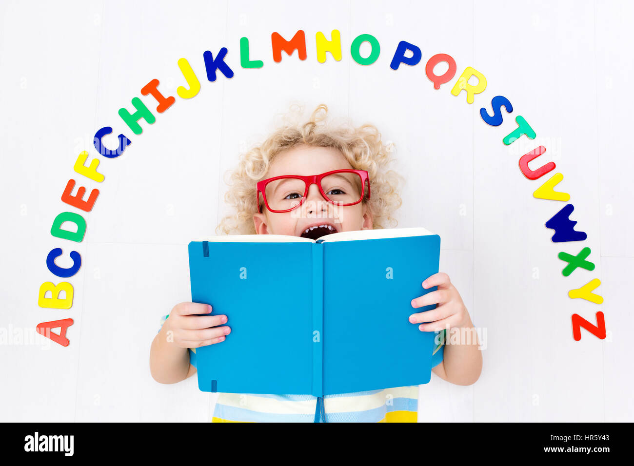 Heureux l'enfant d'âge préscolaire d'apprendre à lire et à écrire en jouant avec les lettres de l'alphabet romain coloré. Abc de l'éducation des jouets et livres pour enfants. Élève de l'école Banque D'Images