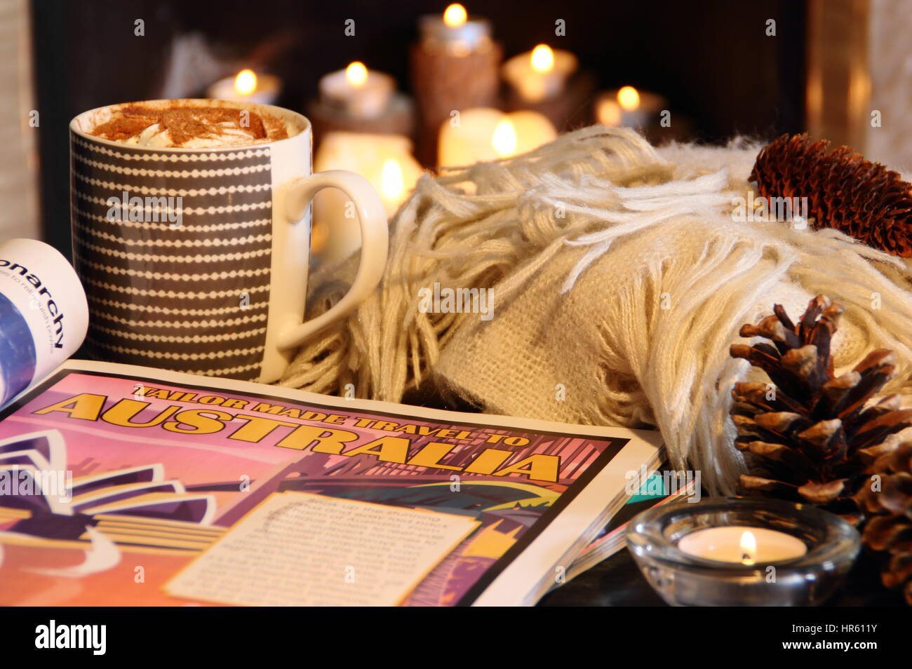 La lecture des magazines de voyage glacé par une cheminée avec une tasse de chocolat chaud et une couverture dans un confortable English accueil sur une sombre soirée d'hiver - 2017 Banque D'Images