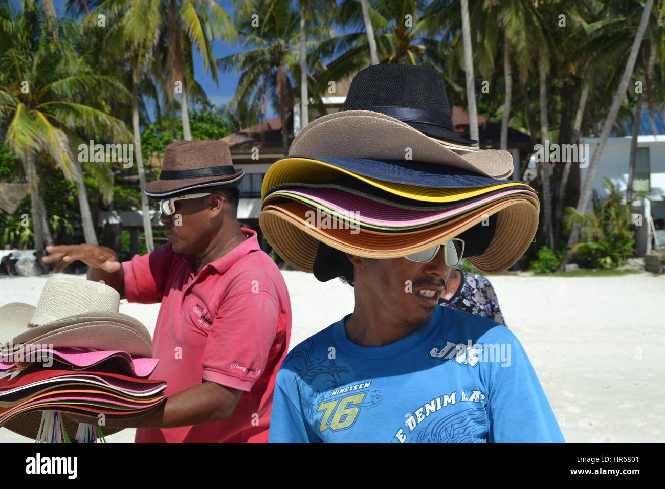 L'homme est la vente de chapeaux sur une plage sur l'île de Boracay.  Beaucoup de chapeaux sur sa tête. protection contre le soleil chaud Photo  Stock - Alamy