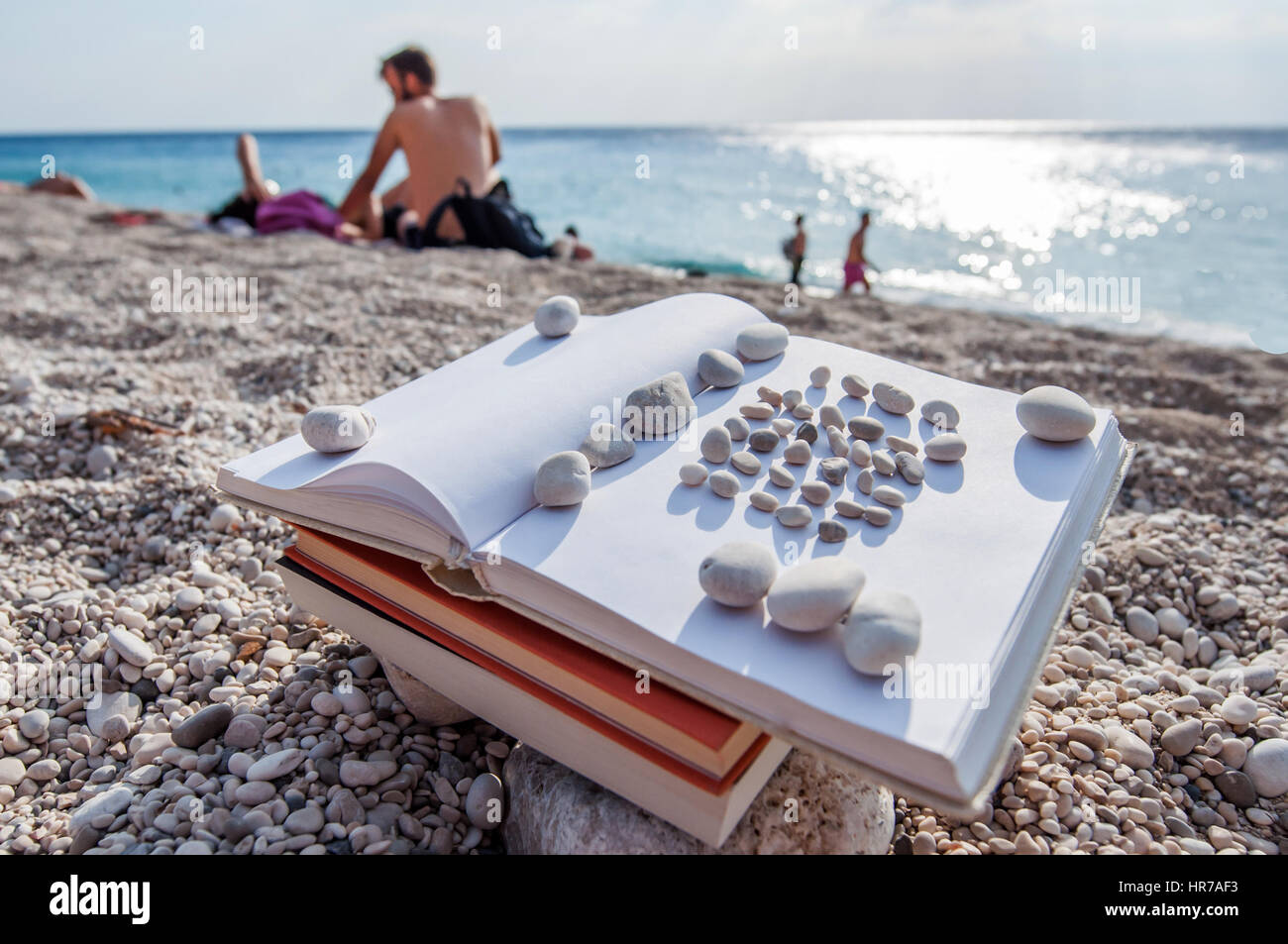 Plage à livre ouvert sur une pile de livres près de la mer en été, coucher du soleil Banque D'Images