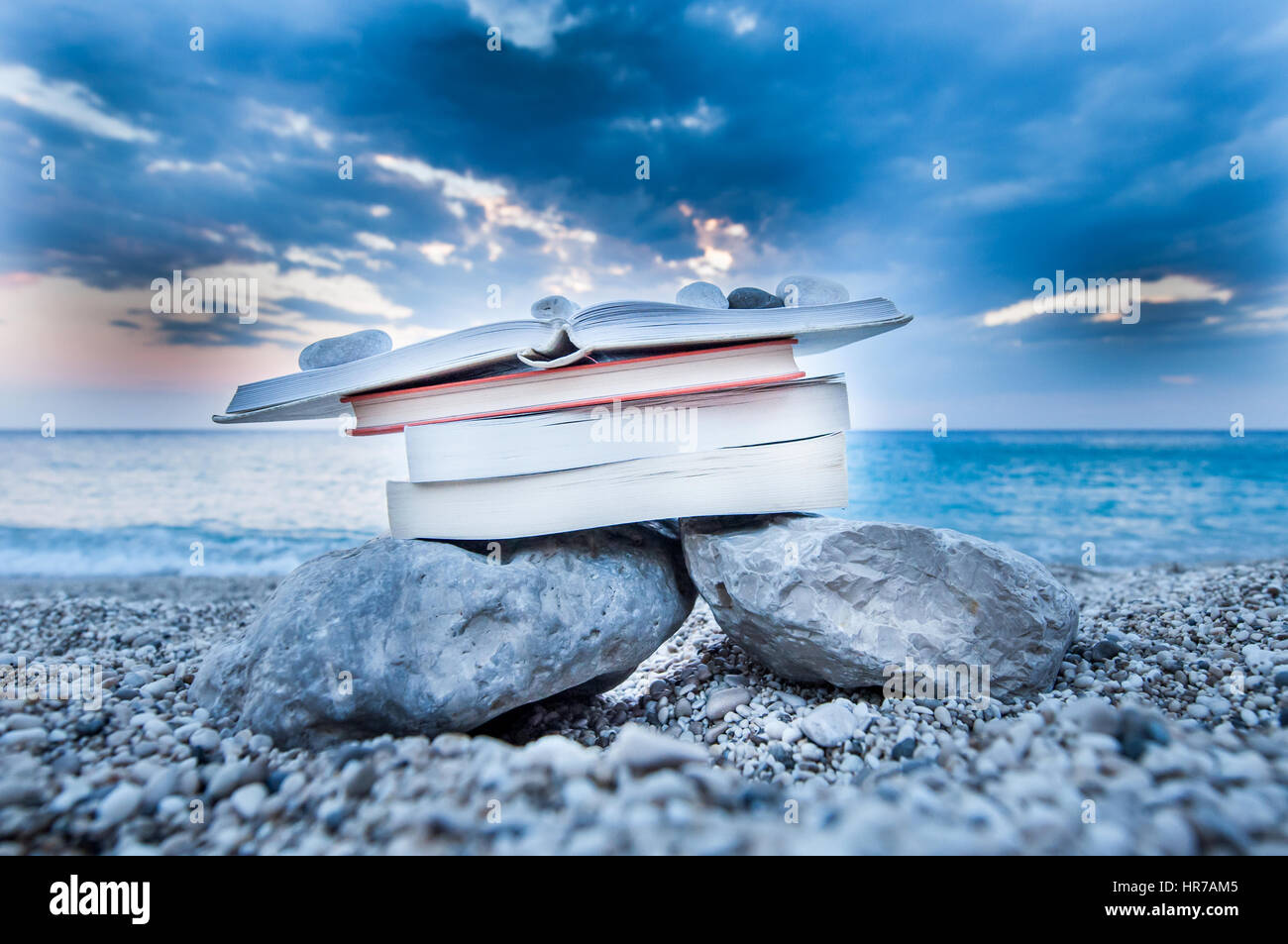 Plage à livre ouvert sur une pile de livres près de la mer en été, coucher du soleil Banque D'Images