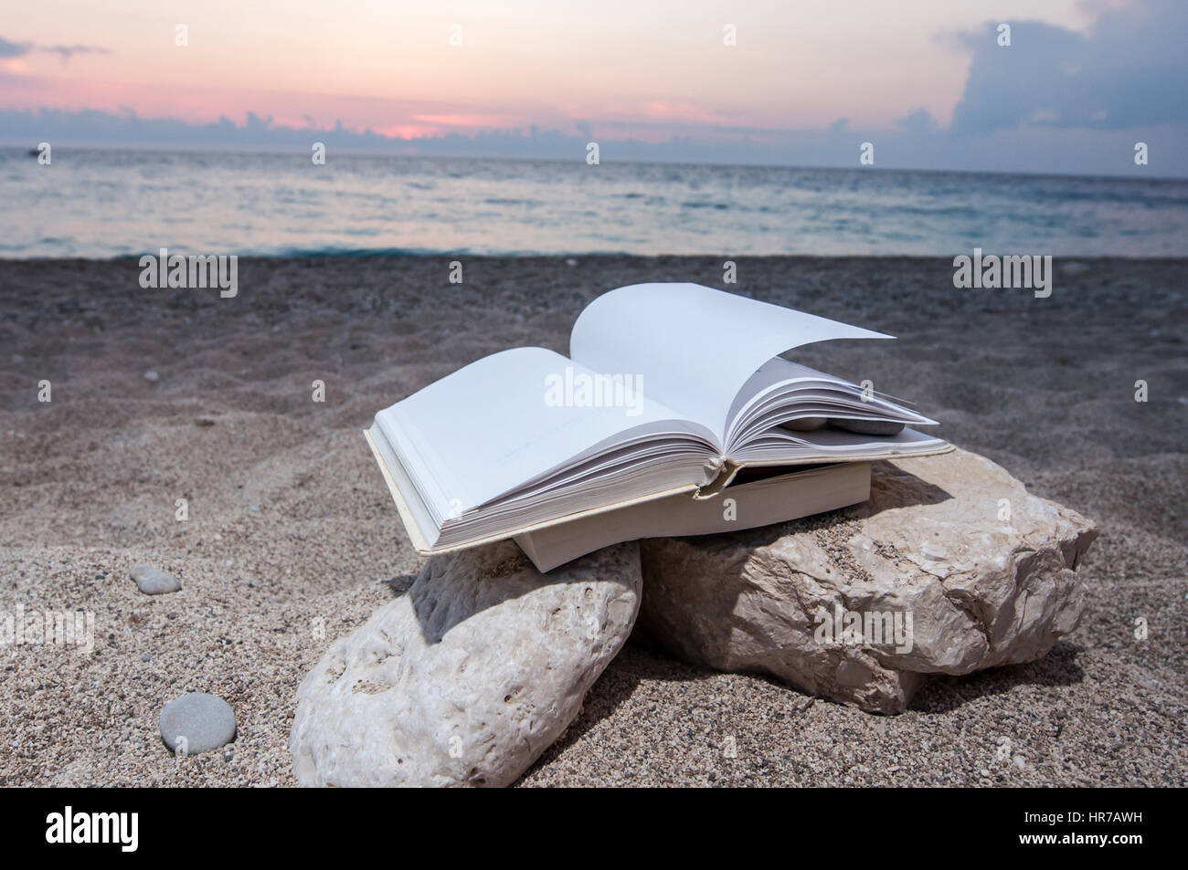 Plage à livre ouvert sur une pile de livres près de la mer en été, coucher du soleil Banque D'Images