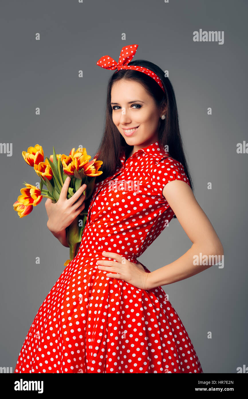 Jolie fille en robe rouge à pois rétro avec des tulipes Banque D'Images