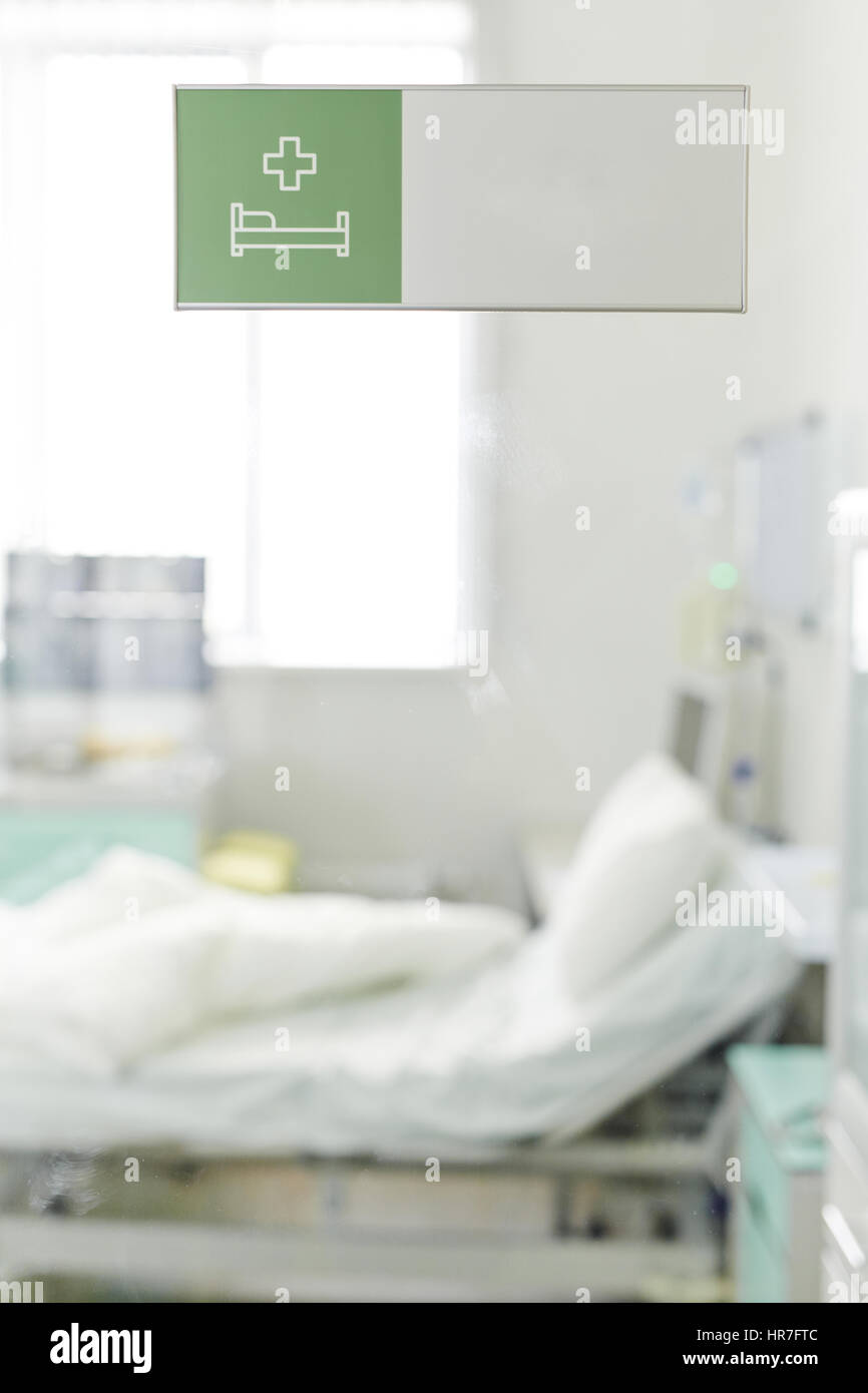 Image de lit vide en clinique avec des draps propres blanc jeté plus que si le patient est maintenant haut et gauche, tourné par porte en verre avec l'Hôpital de vert Banque D'Images