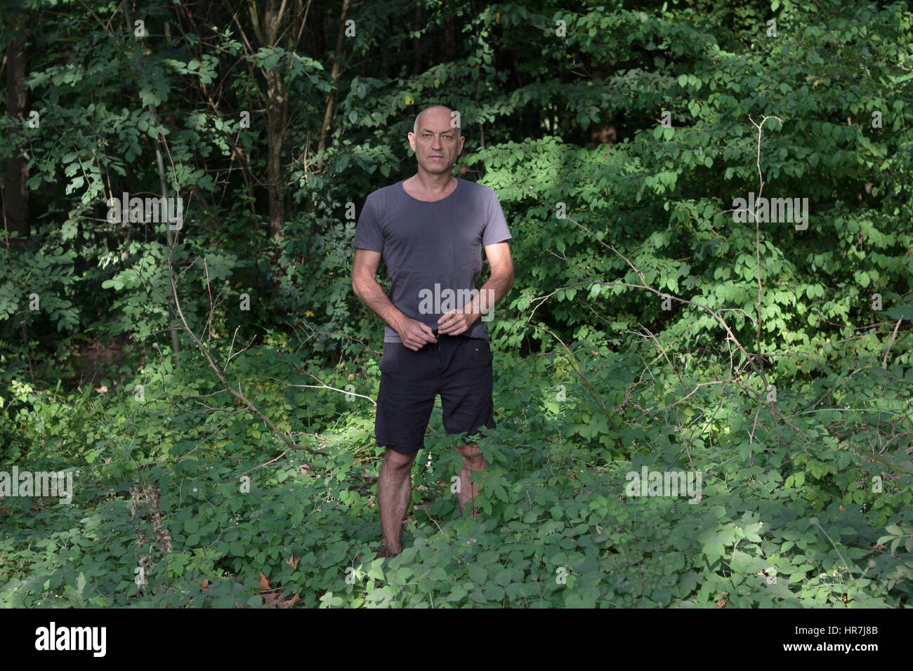 Portrait d'un homme debout dans une forêt entre la prolifération de Banque D'Images