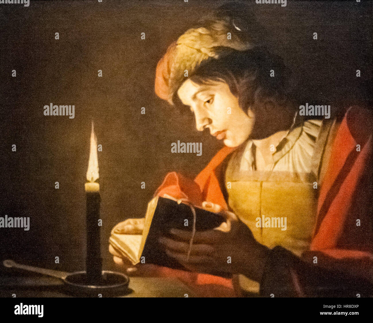 'A Young Man Reading at Candlelight' est une peinture de 1632 de Matthias Some, illustrant le style Ténébrisme avec des contrastes dramatiques de lumière et d'ombre, représentant un jeune homme illuminé par des chandelles. Banque D'Images